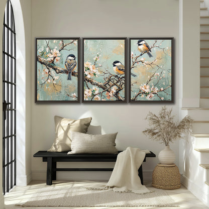 Small colorful songbirds perched among pale blossoms on soft aqua 3 piece framed canvas wall art displayed in a entryway
