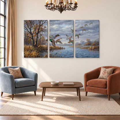 Ducks taking flight over a blue river framed by autumn branches 3 piece canvas wall art styled in an interior