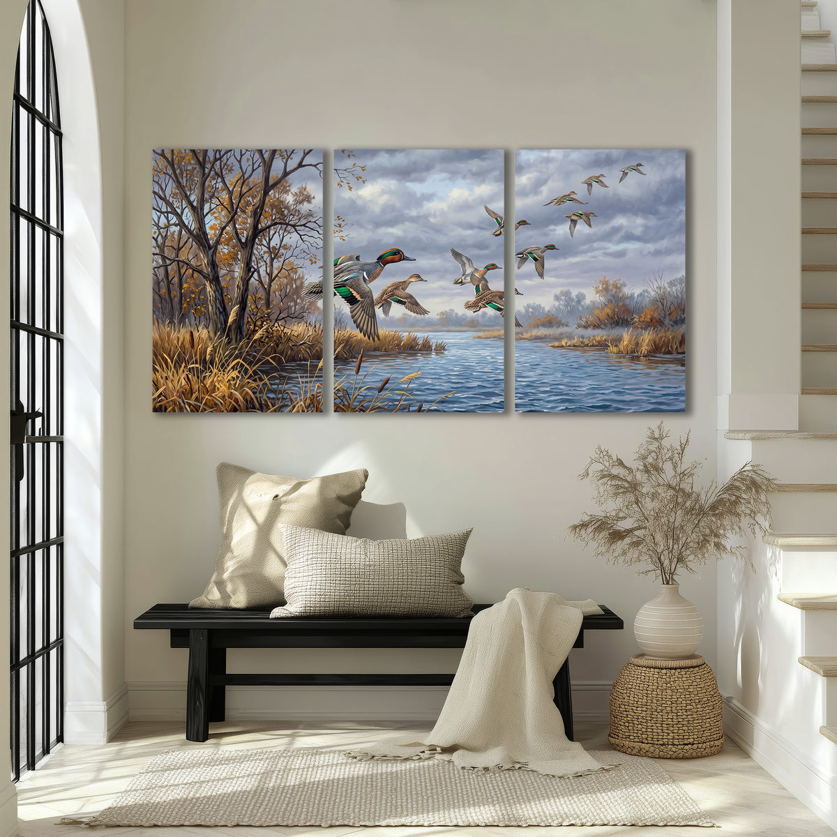 Ducks taking flight over a blue river framed by autumn branches 3 piece canvas wall art displayed in a entryway