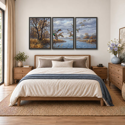 Ducks taking flight over a blue river framed by autumn branches 3 piece framed canvas wall art styled in an interior