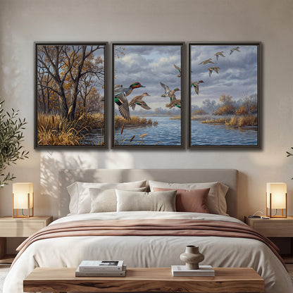 Ducks taking flight over a blue river framed by autumn branches 3 piece framed canvas wall art displayed in a bedroom