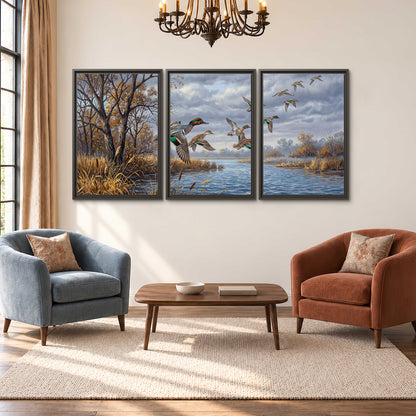 Ducks taking flight over a blue river framed by autumn branches 3 piece framed canvas wall art styled in an interior