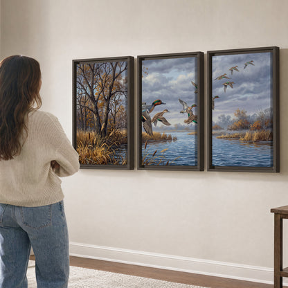 Ducks taking flight over a blue river framed by autumn branches 3 piece framed canvas wall art three panel arrangement on a wall