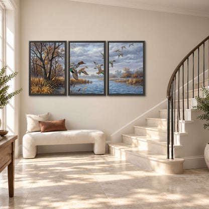 Ducks taking flight over a blue river framed by autumn branches 3 piece framed canvas wall art styled in an interior