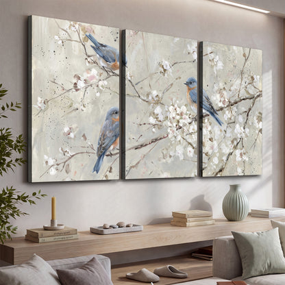Bluebirds perched on delicate white flowering branches against pale sage 3 piece canvas wall art displayed in a console