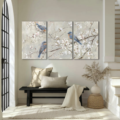 Bluebirds perched on delicate white flowering branches against pale sage 3 piece canvas wall art displayed in a entryway