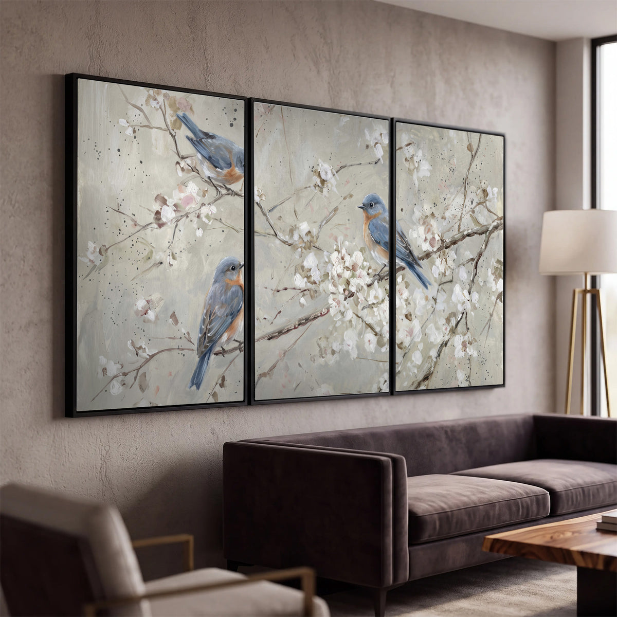 Bluebirds perched on delicate white flowering branches against pale sage 3 piece framed canvas wall art displayed in a modern living room