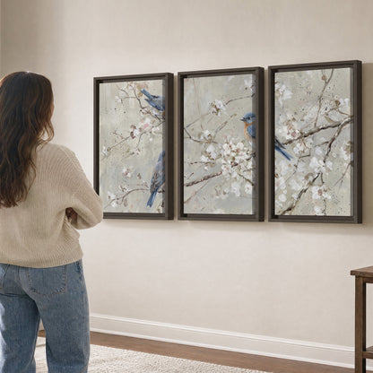 Bluebirds perched on delicate white flowering branches against pale sage 3 piece framed canvas wall art three panel arrangement on a wall