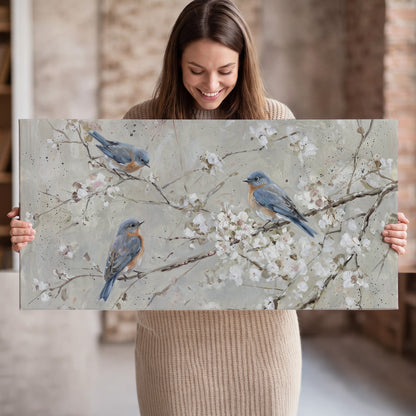 Bluebirds perched on delicate white flowering branches against pale sage single canvas wall art held in hands