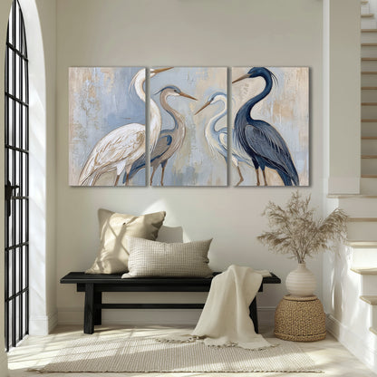 Three long-necked herons in soft ivory and dark blue against pale blue-gray 3 piece canvas wall art displayed in a entryway