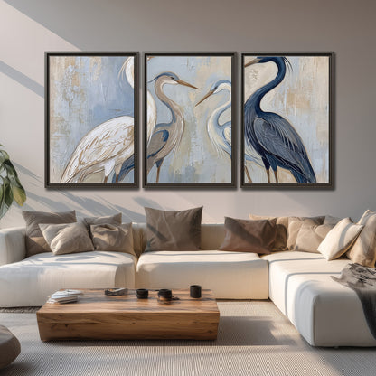 Three long-necked herons in soft ivory and dark blue against pale blue-gray 3 piece framed canvas wall art displayed in a living room
