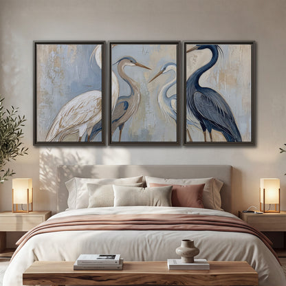 Three long-necked herons in soft ivory and dark blue against pale blue-gray 3 piece framed canvas wall art displayed in a bedroom