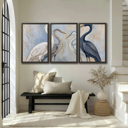 Three long-necked herons in soft ivory and dark blue against pale blue-gray 3 piece framed canvas wall art displayed in a entryway