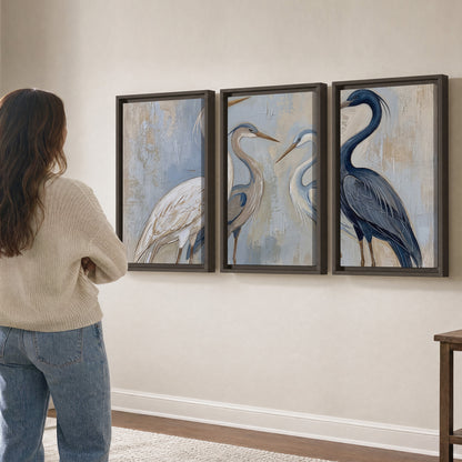 Three long-necked herons in soft ivory and dark blue against pale blue-gray 3 piece framed canvas wall art three panel arrangement on a wall