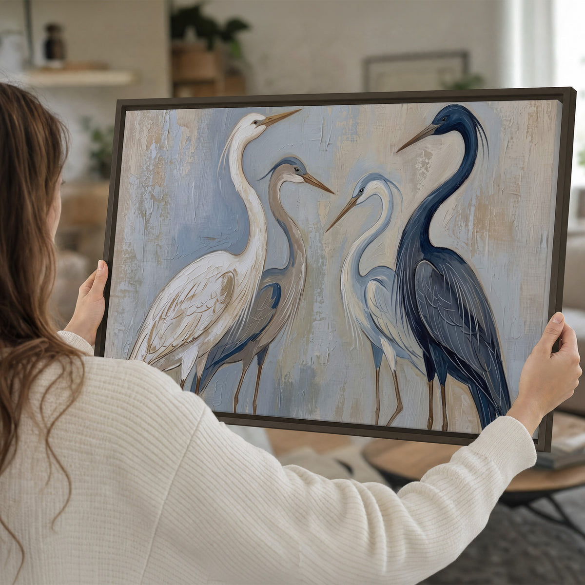 Three long-necked herons in soft ivory and dark blue against pale blue-gray single framed canvas wall art held in hands