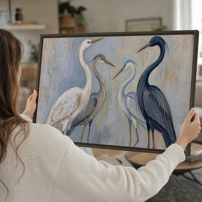 Three long-necked herons in soft ivory and dark blue against pale blue-gray single framed canvas wall art held in hands