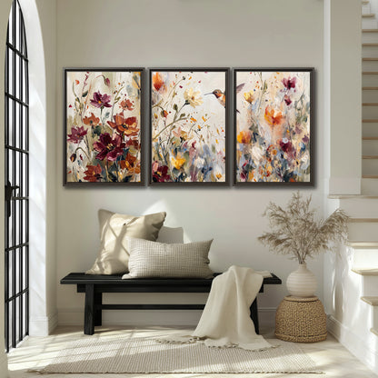 A small hummingbird among delicate pink, rust and ivory flowers 3 piece framed canvas wall art displayed in a entryway