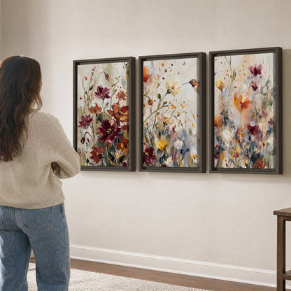 A small hummingbird among delicate pink, rust and ivory flowers 3 piece framed canvas wall art three panel arrangement on a wall