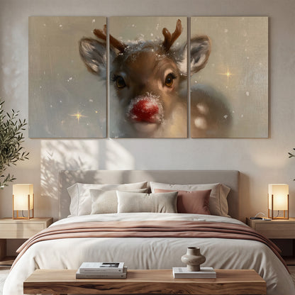 A young reindeer with a bright red nose surrounded by soft snowflakes and tiny painted stars 3 piece canvas wall art displayed in a bedroom