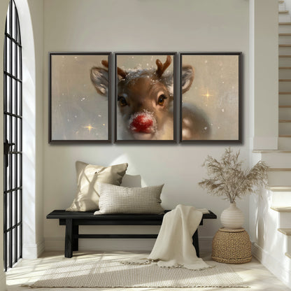 A young reindeer with a bright red nose surrounded by soft snowflakes and tiny painted stars 3 piece framed canvas wall art displayed in a entryway