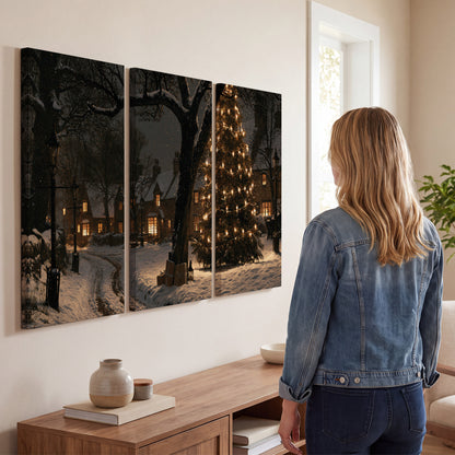 A tall illuminated Christmas tree beneath dark branches beside warmly lit snowy cottages 3 piece canvas wall art three panel arrangement on a wall