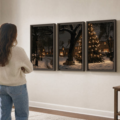 A tall illuminated Christmas tree beneath dark branches beside warmly lit snowy cottages 3 piece framed canvas wall art three panel arrangement on a wall
