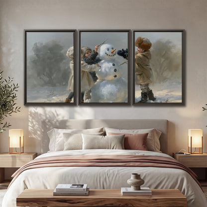 Two children putting the finishing touches on a snowman in a soft snowy landscape 3 piece framed canvas wall art displayed in a bedroom