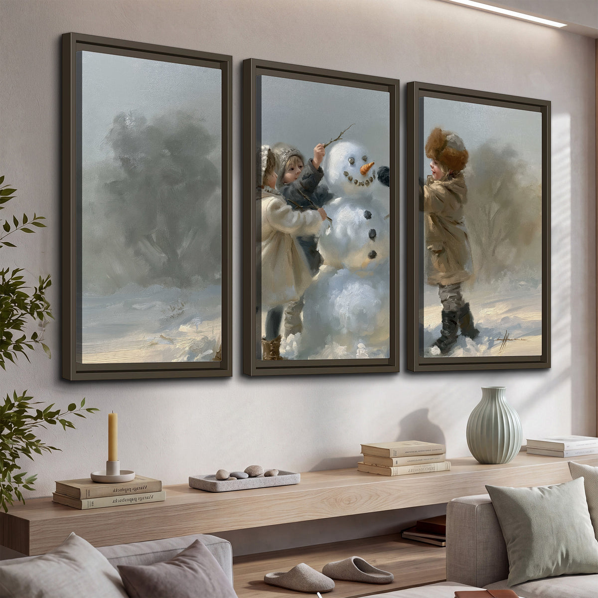 Two children putting the finishing touches on a snowman in a soft snowy landscape 3 piece framed canvas wall art displayed in a console