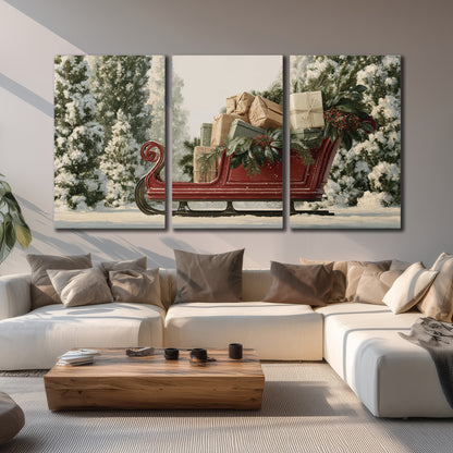 A red sleigh filled with wrapped gifts and evergreen branches among snowy fir trees 3 piece canvas wall art displayed in a living room