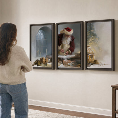 Santa working with dough beside a gingerbread house in a softly lit Christmas kitchen 3 piece framed canvas wall art three panel arrangement on a wall