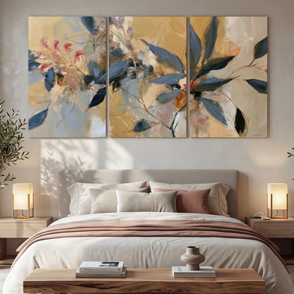Layered navy leaves and muted pink blossoms against a golden cream background 3 piece canvas wall art displayed in a bedroom
