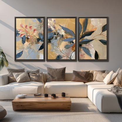 Layered navy leaves and muted pink blossoms against a golden cream background 3 piece framed canvas wall art displayed in a living room