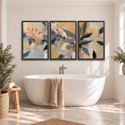 Layered navy leaves and muted pink blossoms against a golden cream background 3 piece framed canvas wall art styled in an interior