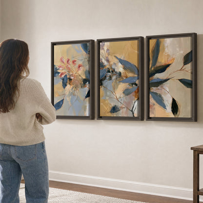Layered navy leaves and muted pink blossoms against a golden cream background 3 piece framed canvas wall art three panel arrangement on a wall