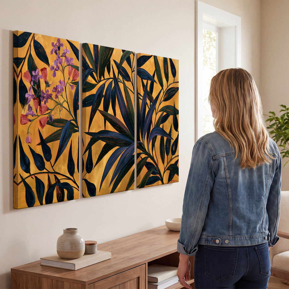 Dark pointed bamboo leaves across an ochre background with small pink floral accents 3 piece canvas wall art three panel arrangement on a wall
