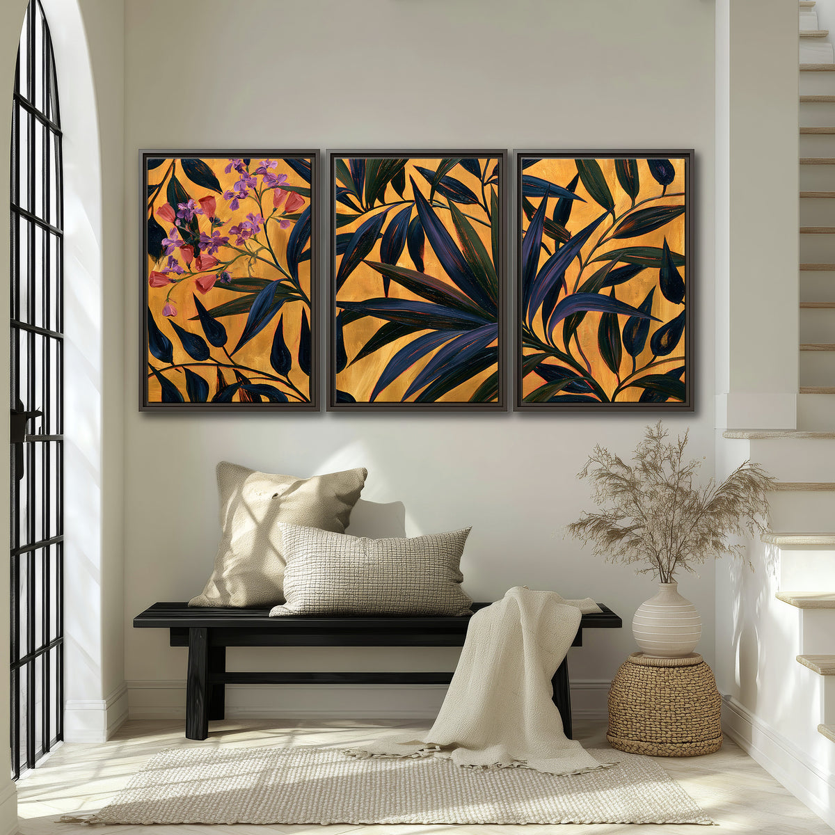 Dark pointed bamboo leaves across an ochre background with small pink floral accents 3 piece framed canvas wall art displayed in a entryway