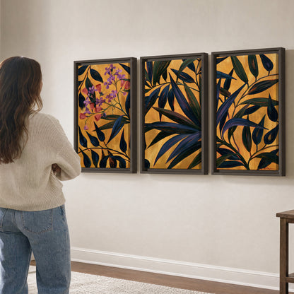 Dark pointed bamboo leaves across an ochre background with small pink floral accents 3 piece framed canvas wall art three panel arrangement on a wall