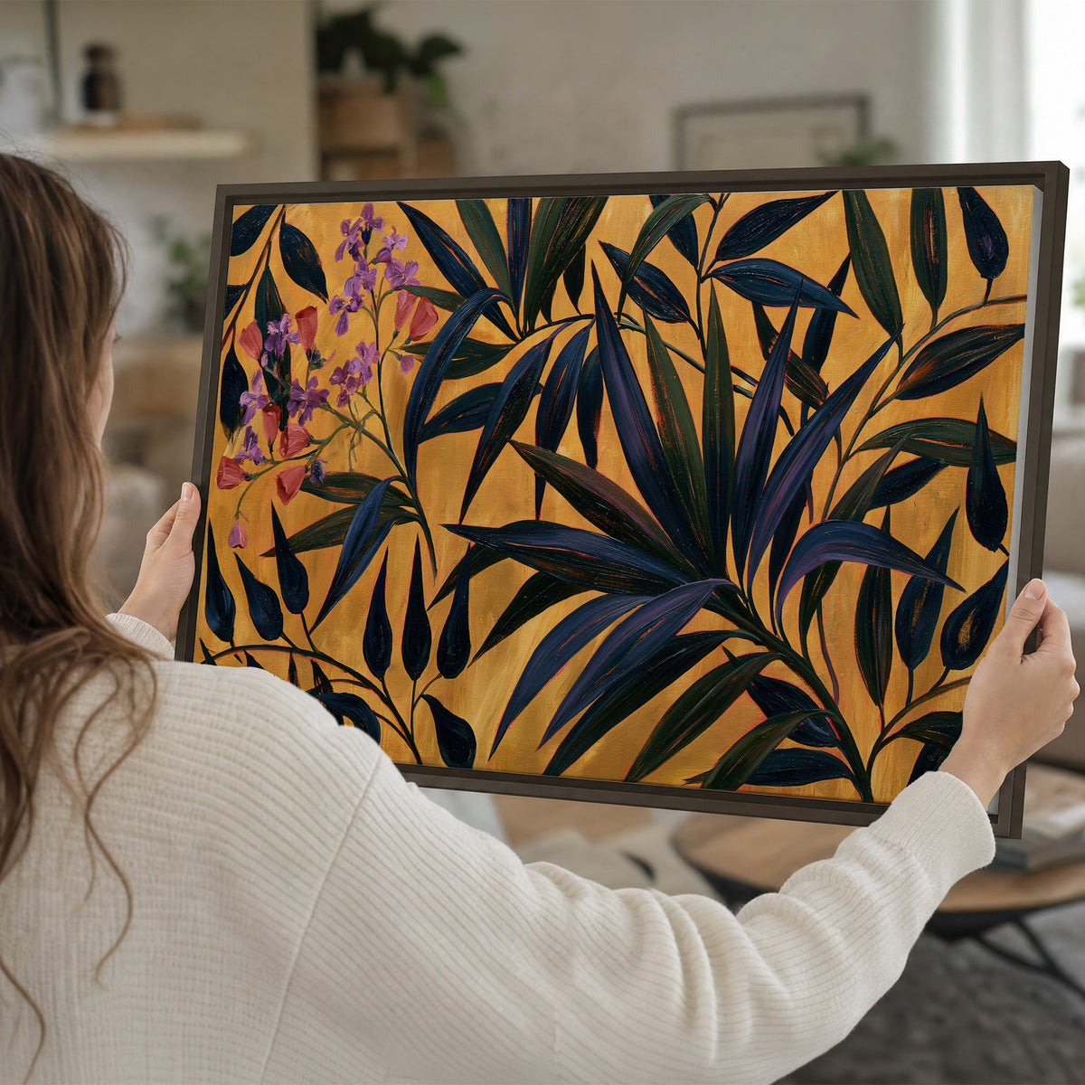 Dark pointed bamboo leaves across an ochre background with small pink floral accents single framed canvas wall art held in hands