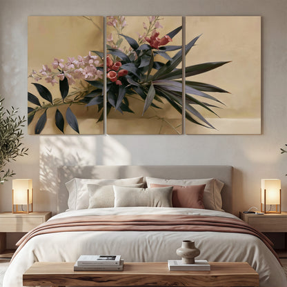 Long dark leaves and dusty pink flowers arranged against a soft beige background 3 piece canvas wall art displayed in a bedroom
