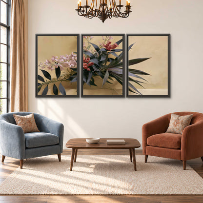 Long dark leaves and dusty pink flowers arranged against a soft beige background 3 piece framed canvas wall art styled in an interior