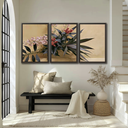 Long dark leaves and dusty pink flowers arranged against a soft beige background 3 piece framed canvas wall art displayed in a entryway