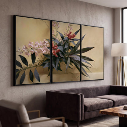 Long dark leaves and dusty pink flowers arranged against a soft beige background 3 piece framed canvas wall art displayed in a modern living room