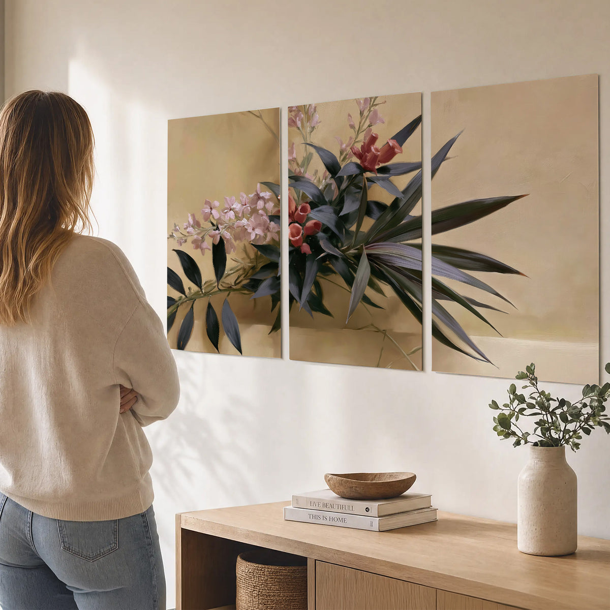 Long dark leaves and dusty pink flowers arranged against a soft beige background set of 3 poster prints three panel arrangement on a wall