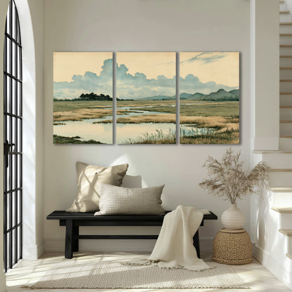 A calm marshland with reflective pools and distant blue-green hills under a clouded sky 3 piece canvas wall art displayed in a entryway