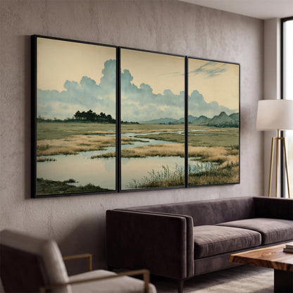 A calm marshland with reflective pools and distant blue-green hills under a clouded sky 3 piece framed canvas wall art displayed in a modern living room