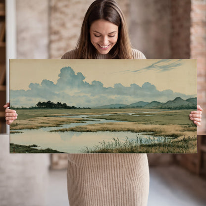 A calm marshland with reflective pools and distant blue-green hills under a clouded sky single canvas wall art held in hands