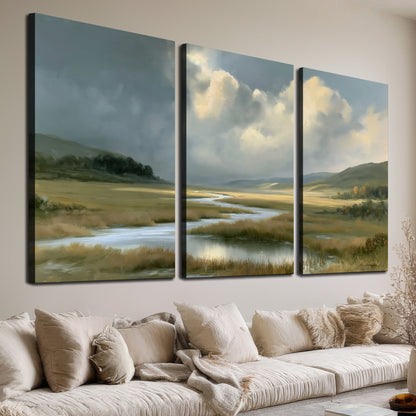 A winding stream through an open meadow beneath large sunlit clouds 3 piece canvas wall art room and product view