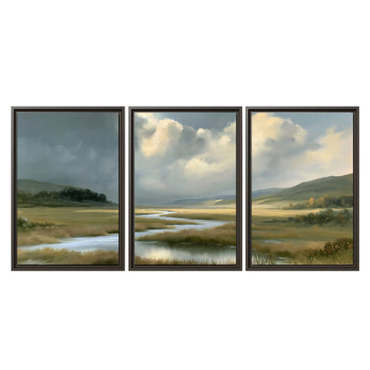 A winding stream through an open meadow beneath large sunlit clouds 3 piece framed canvas wall art viewed straight on
