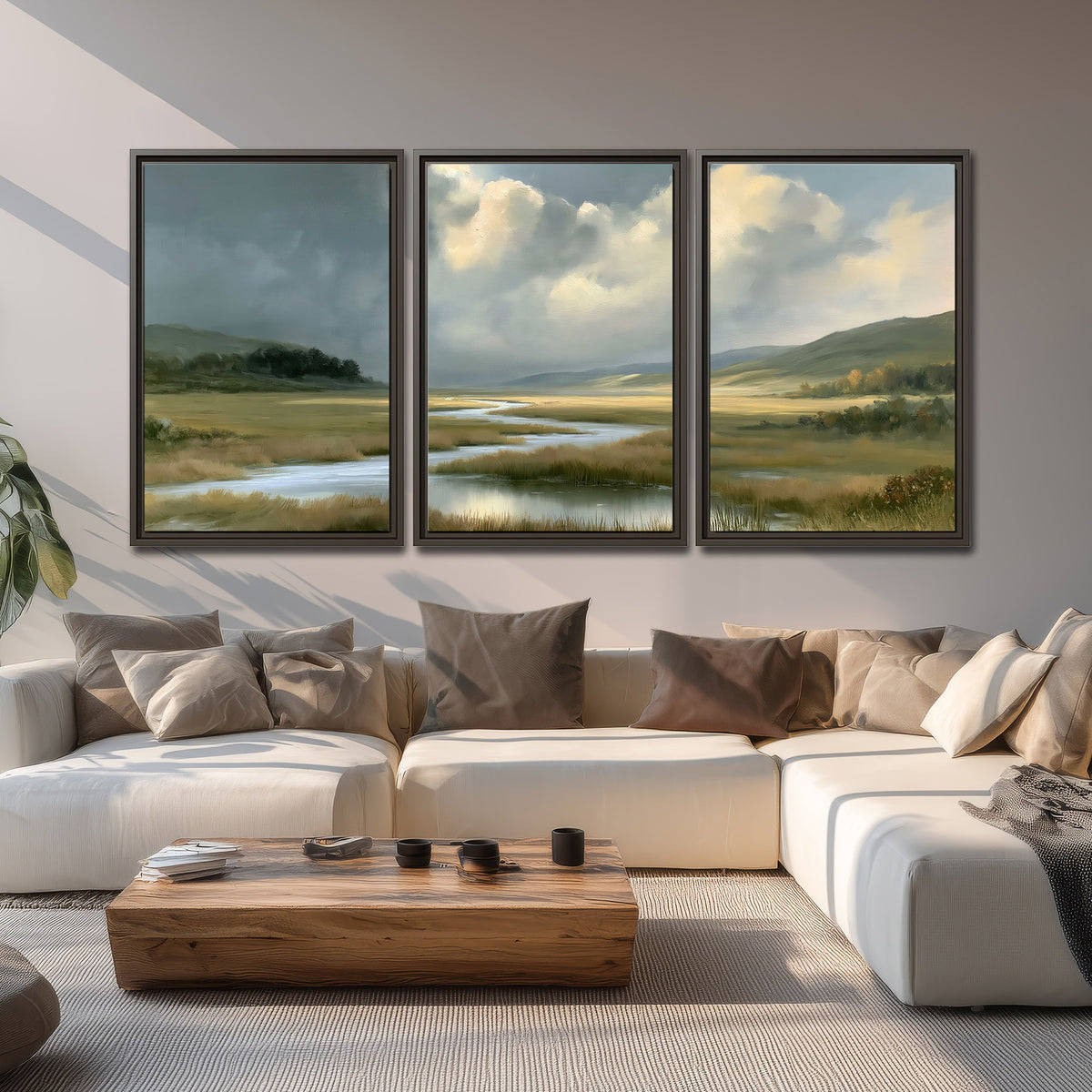 A winding stream through an open meadow beneath large sunlit clouds 3 piece framed canvas wall art displayed in a living room