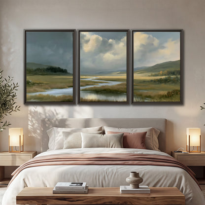 A winding stream through an open meadow beneath large sunlit clouds 3 piece framed canvas wall art displayed in a bedroom